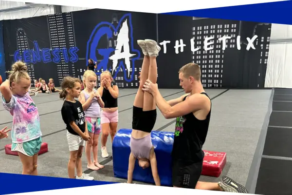 Coach spotting a young athlete on a handstand drill during an intro tumbling class