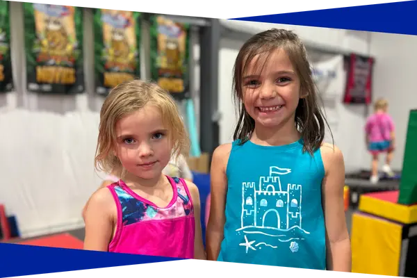 Two young preschool tumbling students smiling in the Genesis Athletix gym