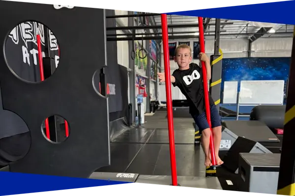 Ninja athlete gripping vertical poles on an advanced obstacle rig
