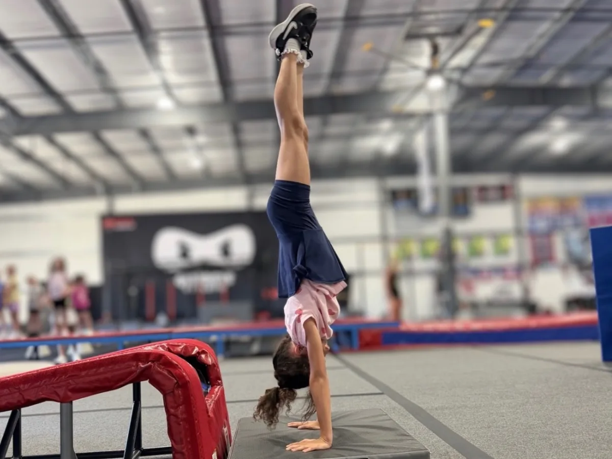 Young athlete holding a handstand during an intro tumbling class at Genesis Athletix